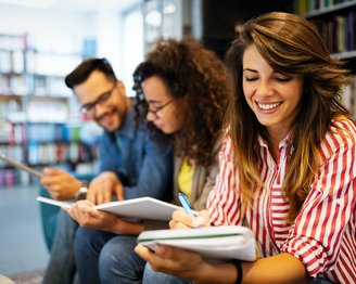 Drei Studierende sitzen nebeneinander in der Bibliothek