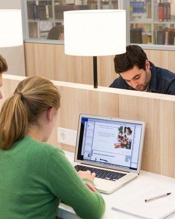 Studenten recherchieren am Laptop in der Bibliothek