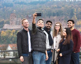 Internationale Studierende schießen ein Foto auf der alten Brücke in Heidelberg