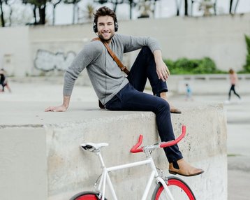 Junger Mann auf Mauer mit seinem Fahrrad im Vordergrund